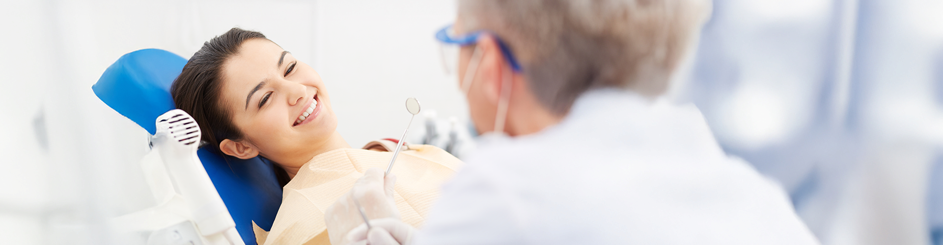 Girl in dental chair smiling at dentist.